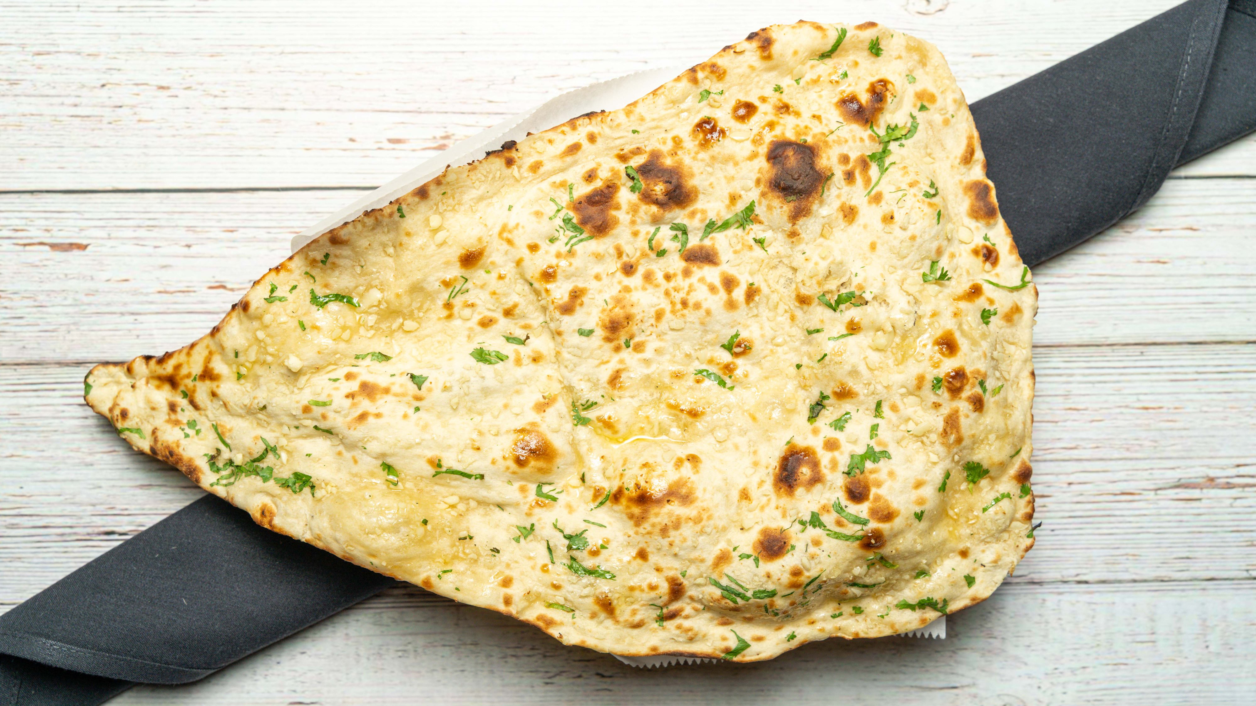 Order 30. Garlic Naan food online from Bombay Cafe store, Wilton Manors on bringmethat.com