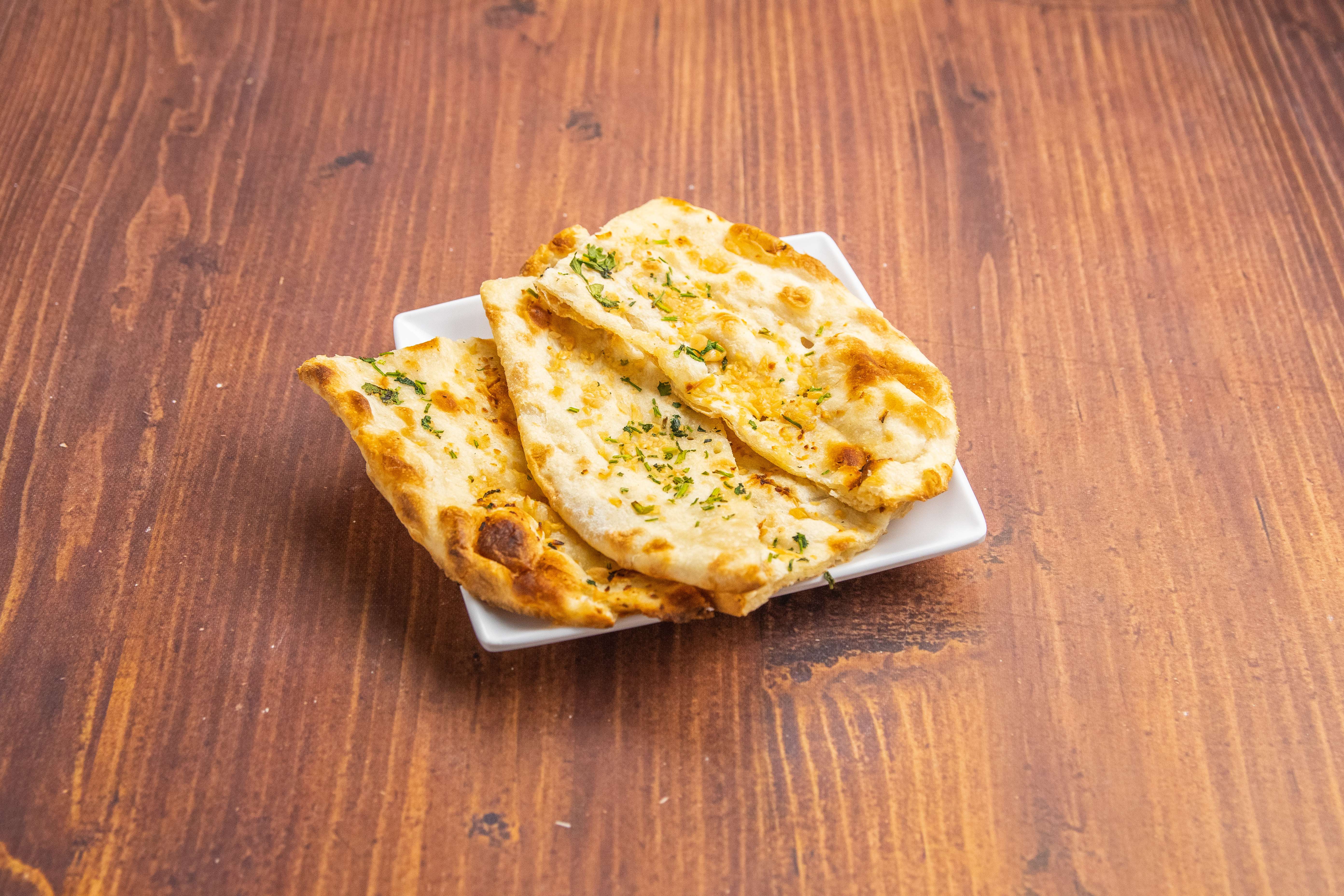 Order 81. Garlic Naan food online from The India Cafe store, Costa Mesa on bringmethat.com