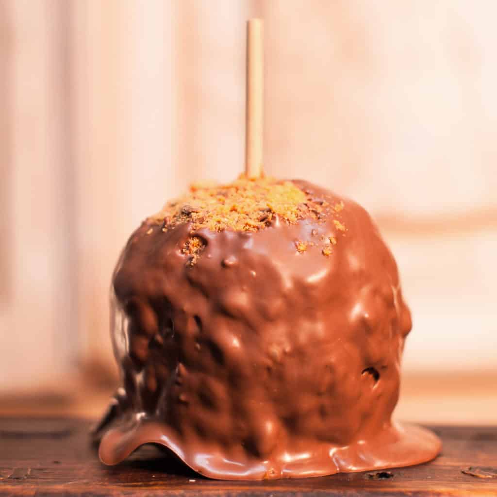 Order Caramel Apple covered in Butterfinger® and topped with Milk Chocolate food online from Candy Apple Shoppe store, Glenwood on bringmethat.com