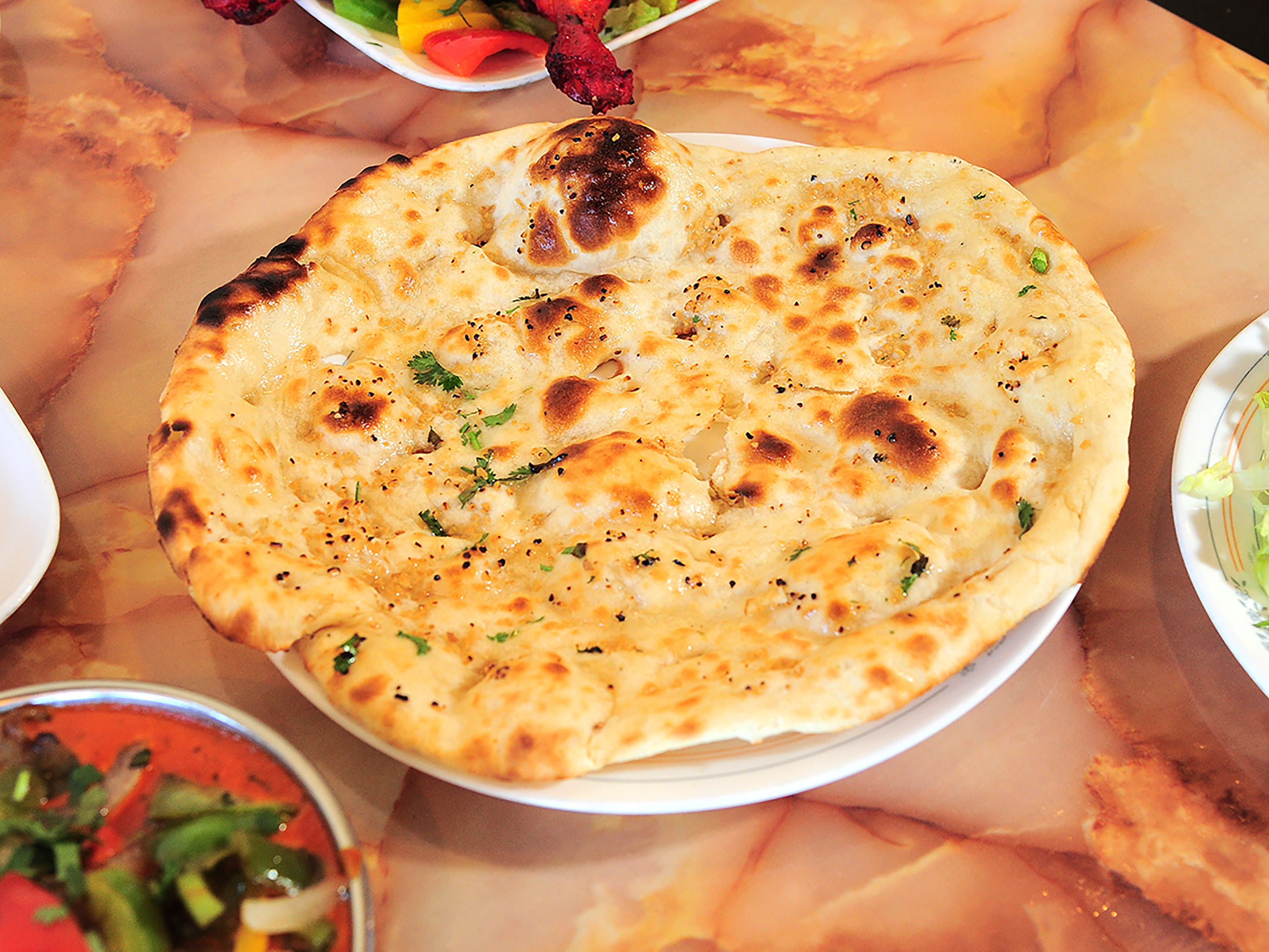 Order 37. Garlic Naan food online from Haveli Indian Cuisine store, Rochester on bringmethat.com
